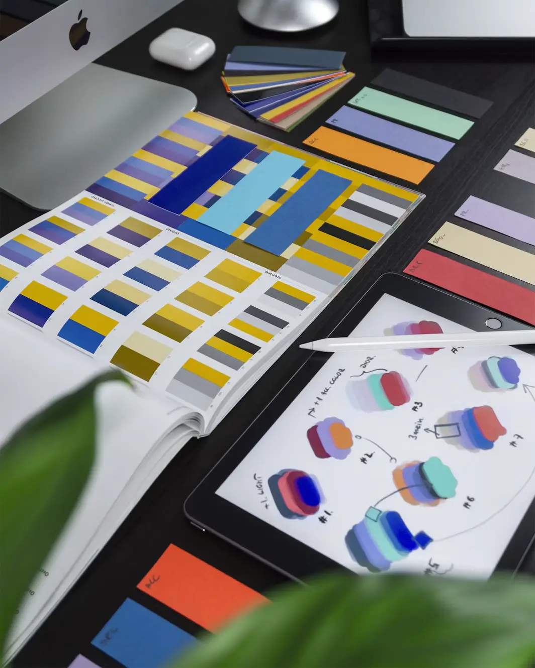 Arbeidsplass med fargeprøver og digitale designskisser